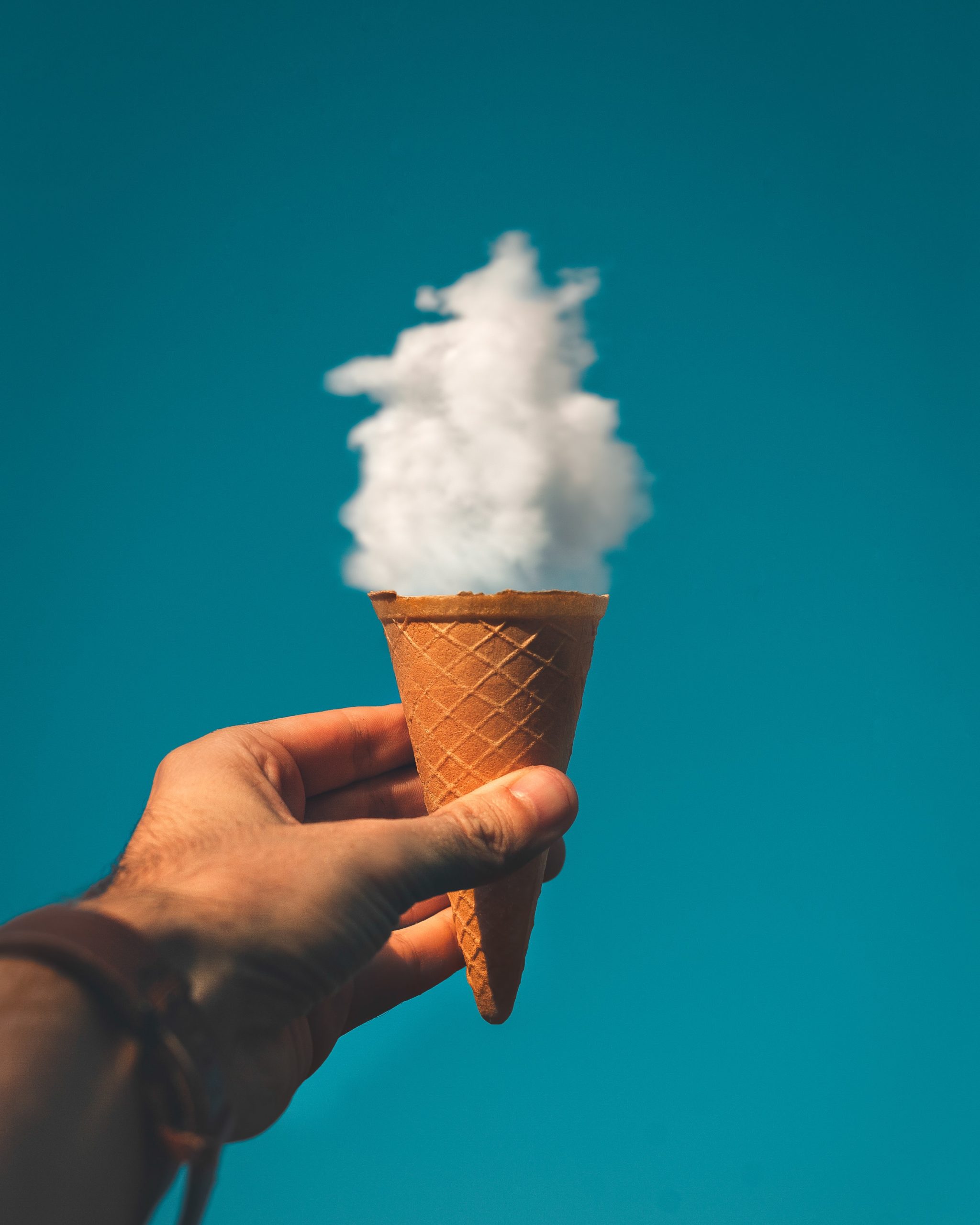 Hand holding ice cream cone with cloud inside it instead of ice cream